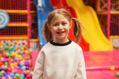 Photo of Happy little girl in ball pit. Kid's play room