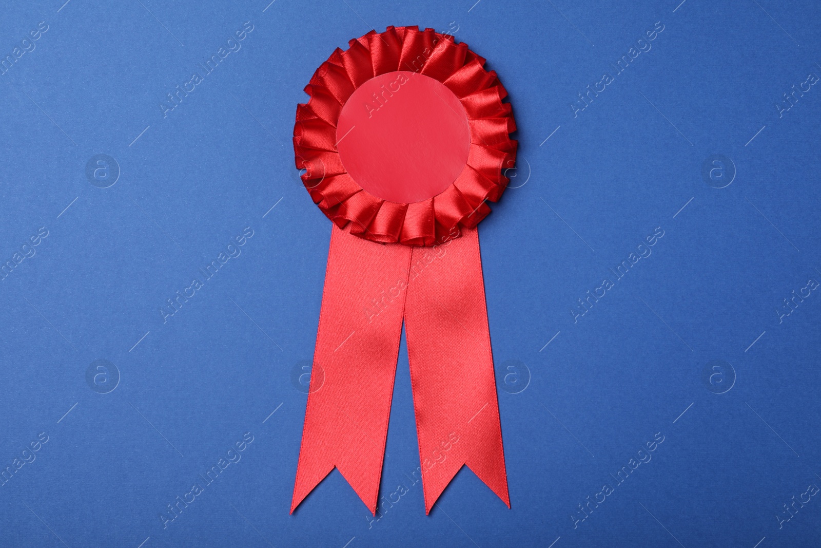 Photo of Red award ribbon on blue background, top view