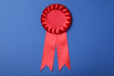 Photo of Red award ribbon on blue background, top view