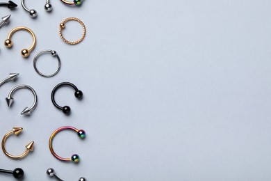 Photo of Stylish piercing jewelry on light grey background, flat lay. Space for text