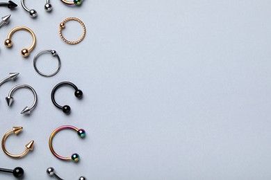 Stylish piercing jewelry on light grey background, flat lay. Space for text