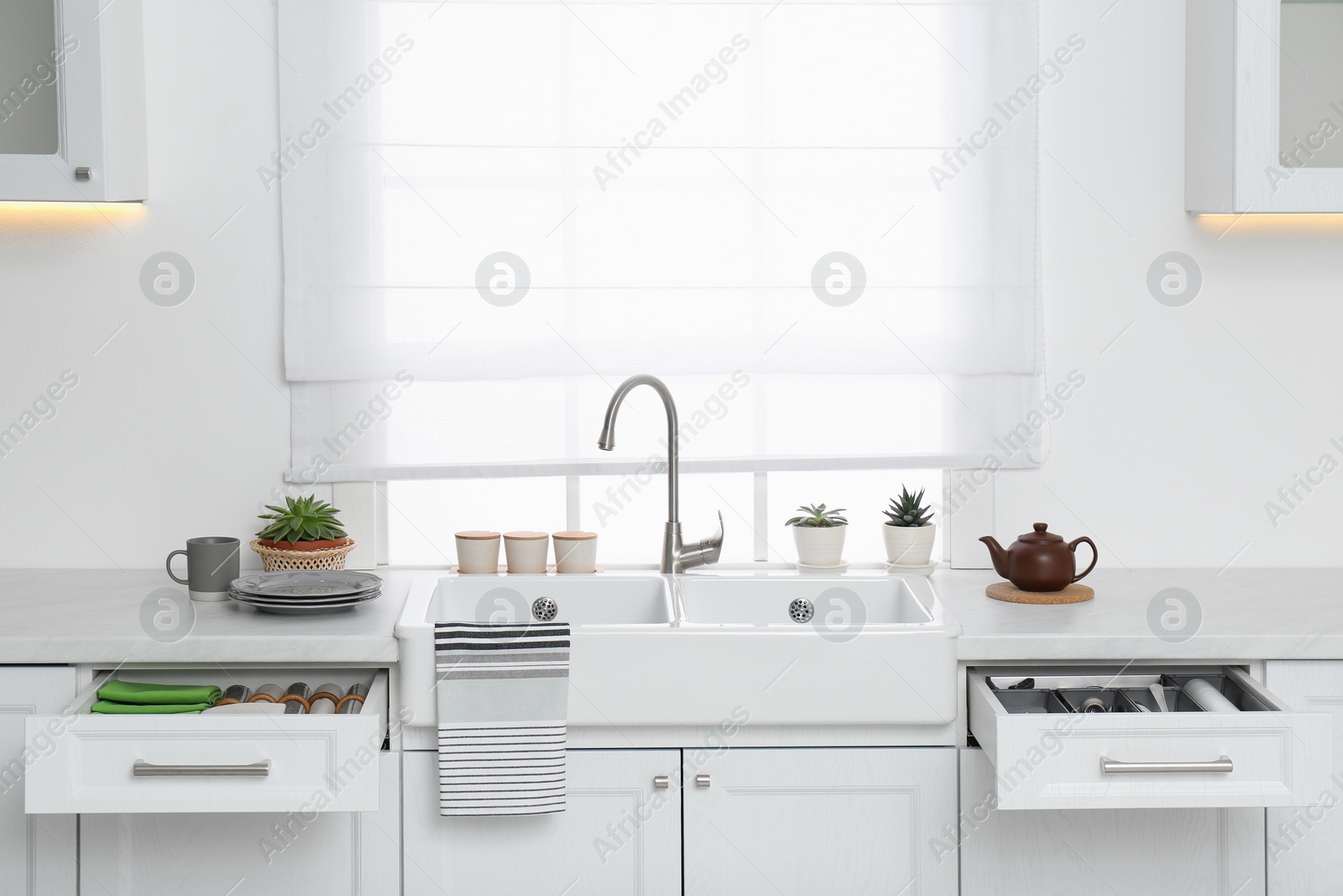 Photo of Open drawers with different utensils, towels and napkins in kitchen