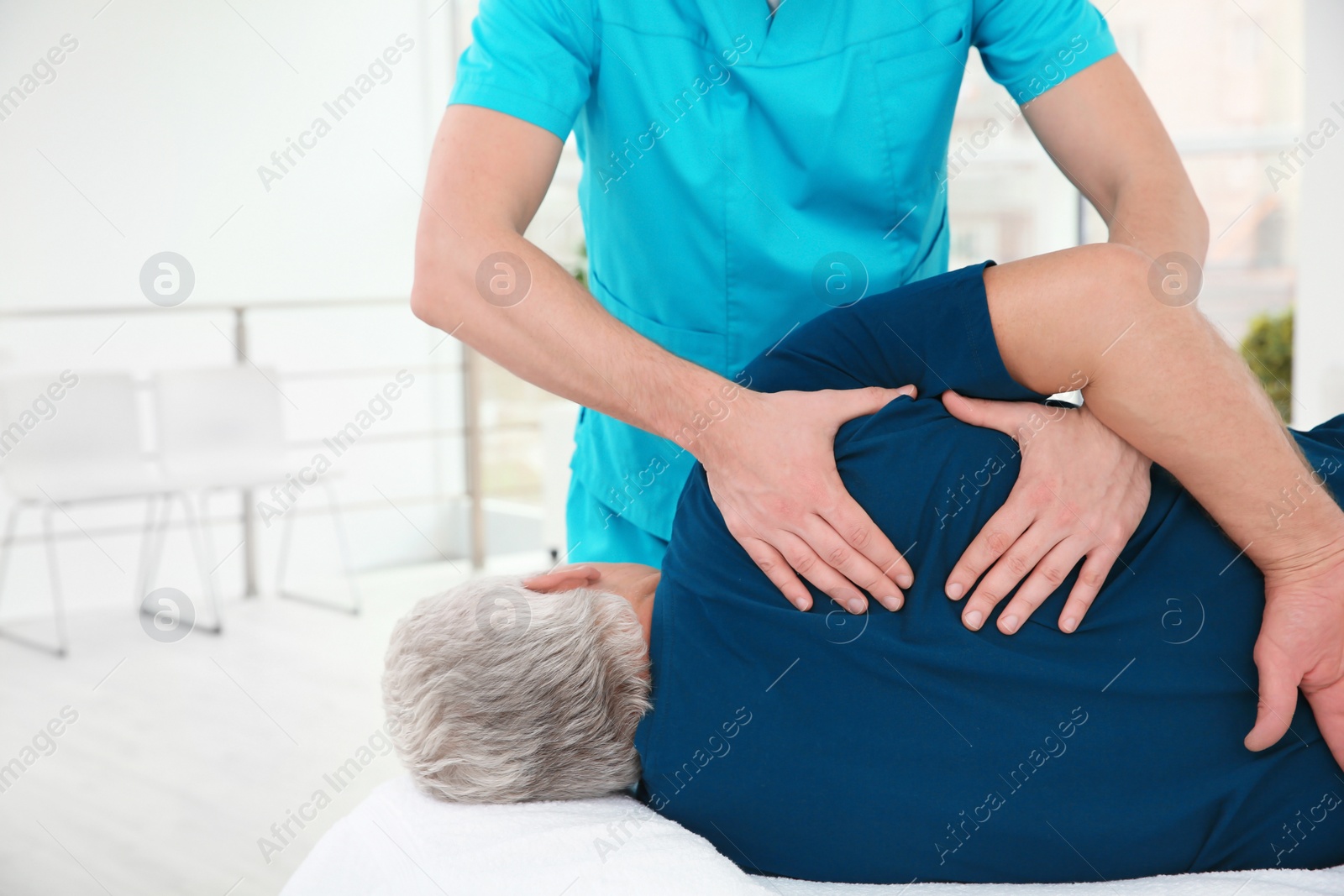 Photo of Young physiotherapist working with senior patient in clinic