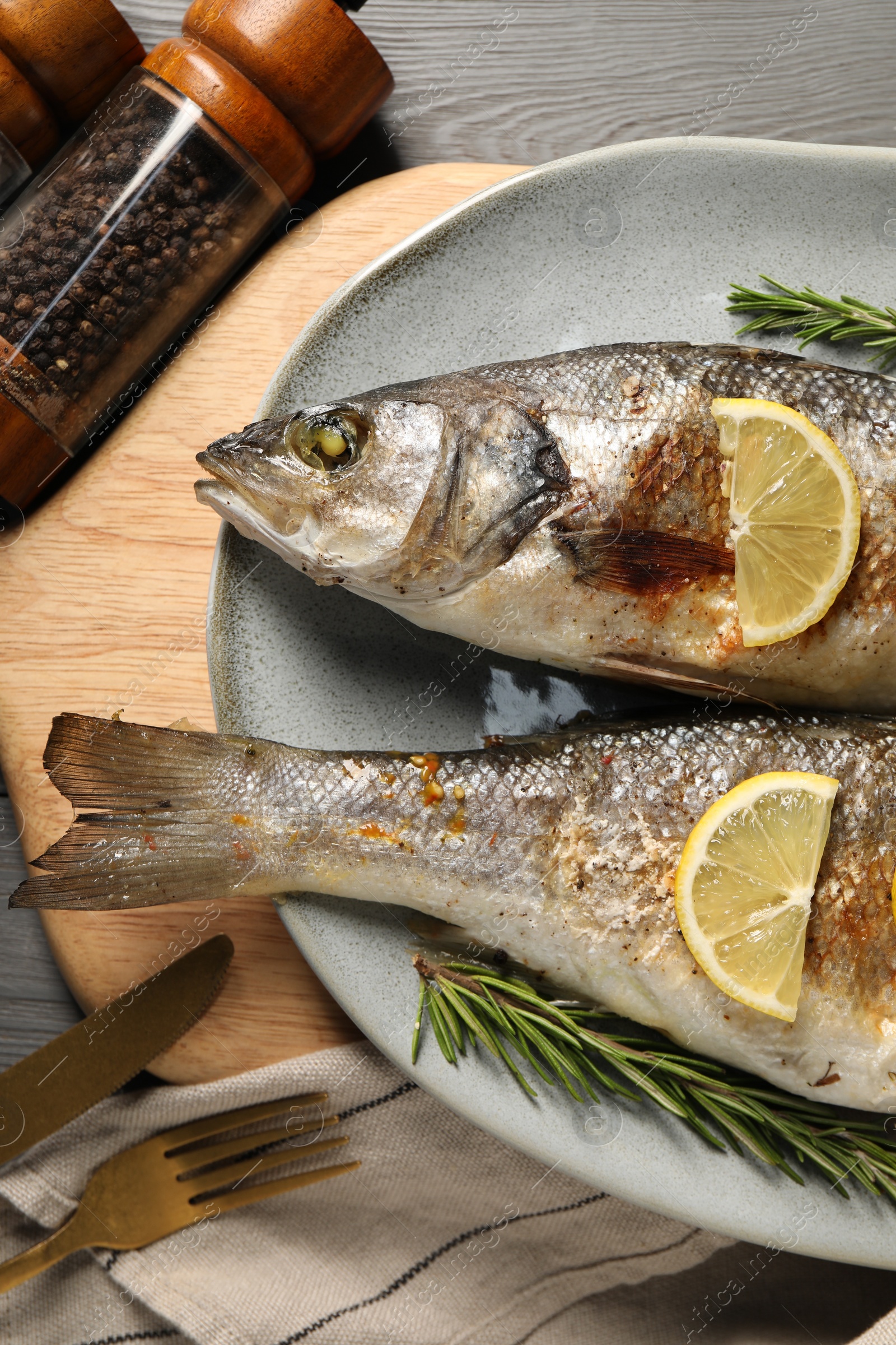 Photo of Delicious baked fish served on grey wooden table, top view