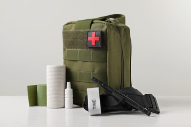Photo of Military first aid kit, tourniquet, drops and elastic bandage on white table