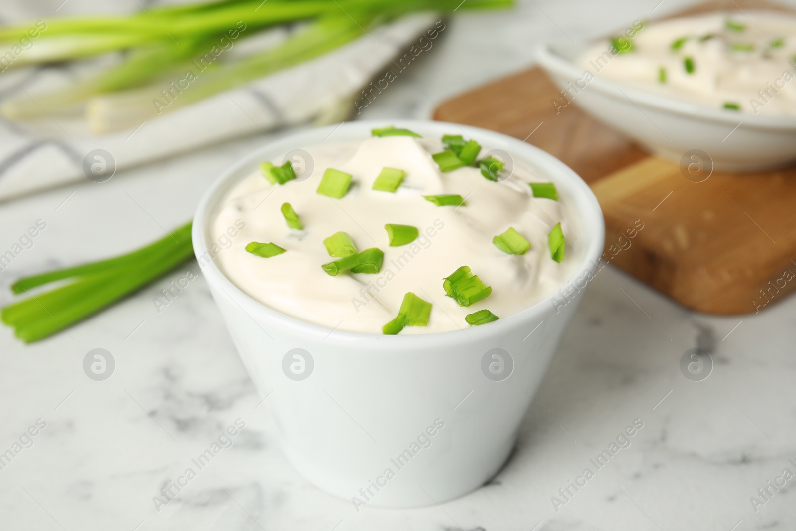 Photo of Fresh sour cream with onion on white marble table