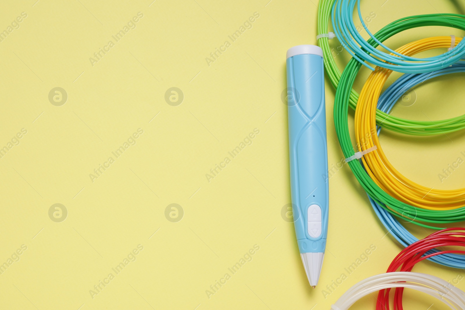 Photo of Stylish 3D pen and colorful plastic filaments on pale yellow background, flat lay. Space for text