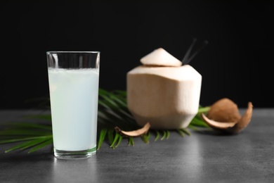 Photo of Glass with fresh coconut water on table against black background