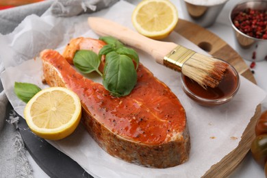 Photo of Fresh marinade, fish, lemon, brush and basil on table, closeup