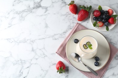 Tasty yogurt in glass and berries on white marble table, flat lay. Space for text