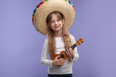 Cute girl in Mexican sombrero hat playing ukulele on purple background