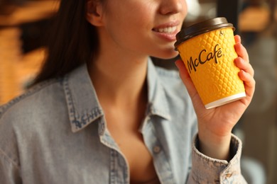 Lviv, Ukraine - September 26, 2023: Woman with hot McDonald's drink in cafe, closeup