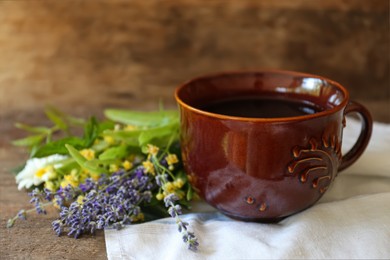 Photo of Tasty herbal tea, fresh lavender flowers and linden branches on wooden table, closeup