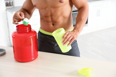 Young shirtless athletic man preparing protein shake in kitchen, closeup view