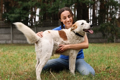 Photo of Female volunteer with homeless dog at animal shelter outdoors