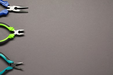 Photo of Different pliers on grey background, flat lay. Space for text