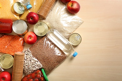 Photo of Many different products and space for text on wooden background, flat lay. Food donation