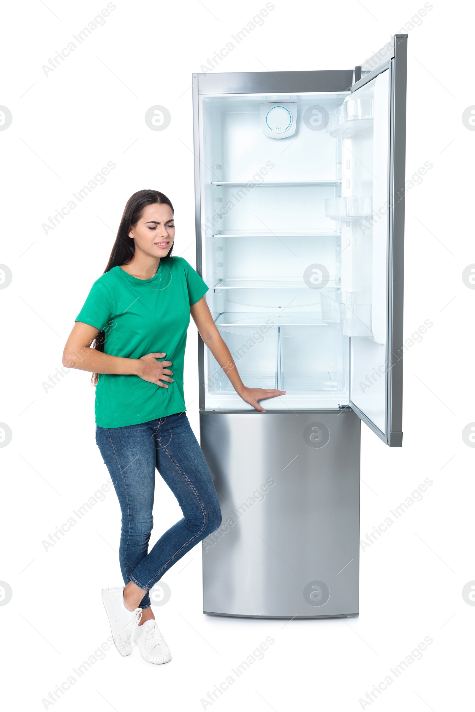 Photo of Hungry woman near empty refrigerator on white background