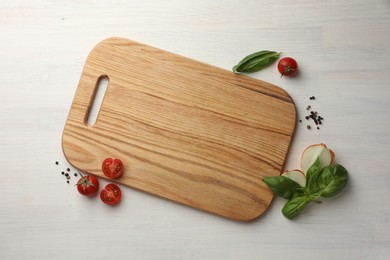 Photo of Cutting board, basil, onion, pepper and tomatoes on white wooden table, flat lay. Space for text