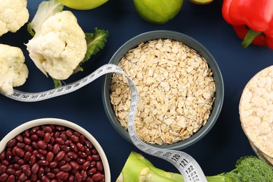 Photo of Healthy diet. Different products and measuring tape on blue wooden table, flat lay