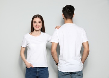 Photo of Young people in t-shirts on light background. Mock up for design