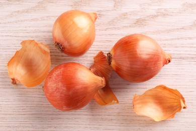 Photo of Raw ripe onions on wooden table, flat lay