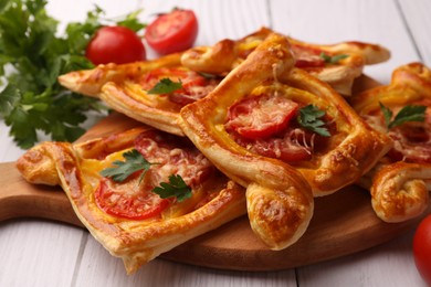 Fresh delicious puff pastry with cheese, tomatoes and parsley on white wooden table, closeup