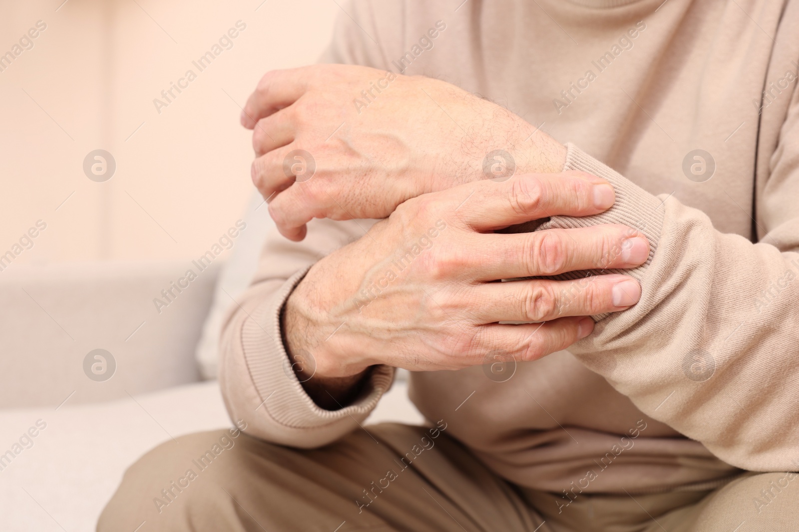 Photo of Senior man suffering from pain in his wrist at home, closeup. Arthritis symptoms