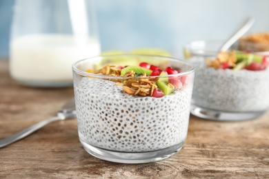 Dessert bowl of tasty chia seed pudding with granola, kiwi and pomegranate on table