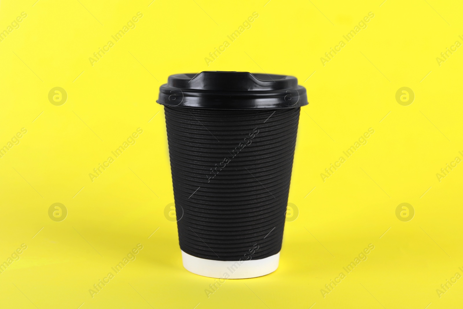 Photo of Black paper cup with plastic lid on yellow background. Coffee to go