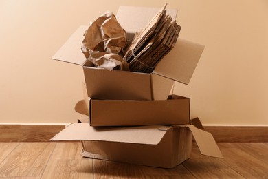 Photo of Heap of waste paper on wooden floor near beige wall