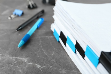 Photo of Stack of documents with binder clips on grey stone table, closeup view. Space for text