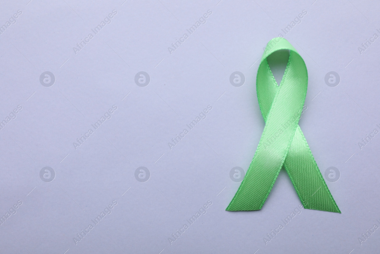 Photo of World Mental Health Day. Green ribbon on color background, top view with space for text