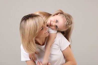 Family portrait of happy mother and daughter on grey background