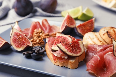 Photo of Sandwich with ripe fig and delicious products on grey plate, closeup