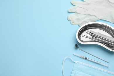 Photo of Set of different dentist's tools, face mask and gloves on light blue background, flat lay. Space for text