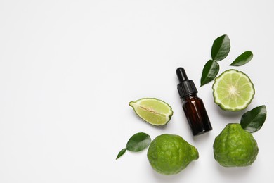 Glass bottle of bergamot essential oil and fresh fruits on white background, flat lay. Space for text