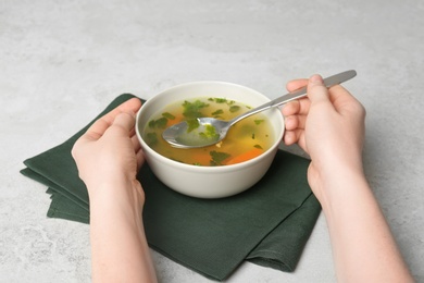 Photo of Young woman with bowl of hot broth at table. Cold treatment