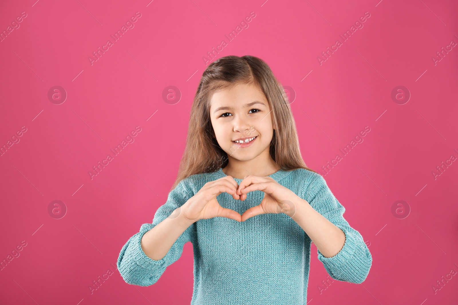 Photo of Girl making heart with her hands on color background