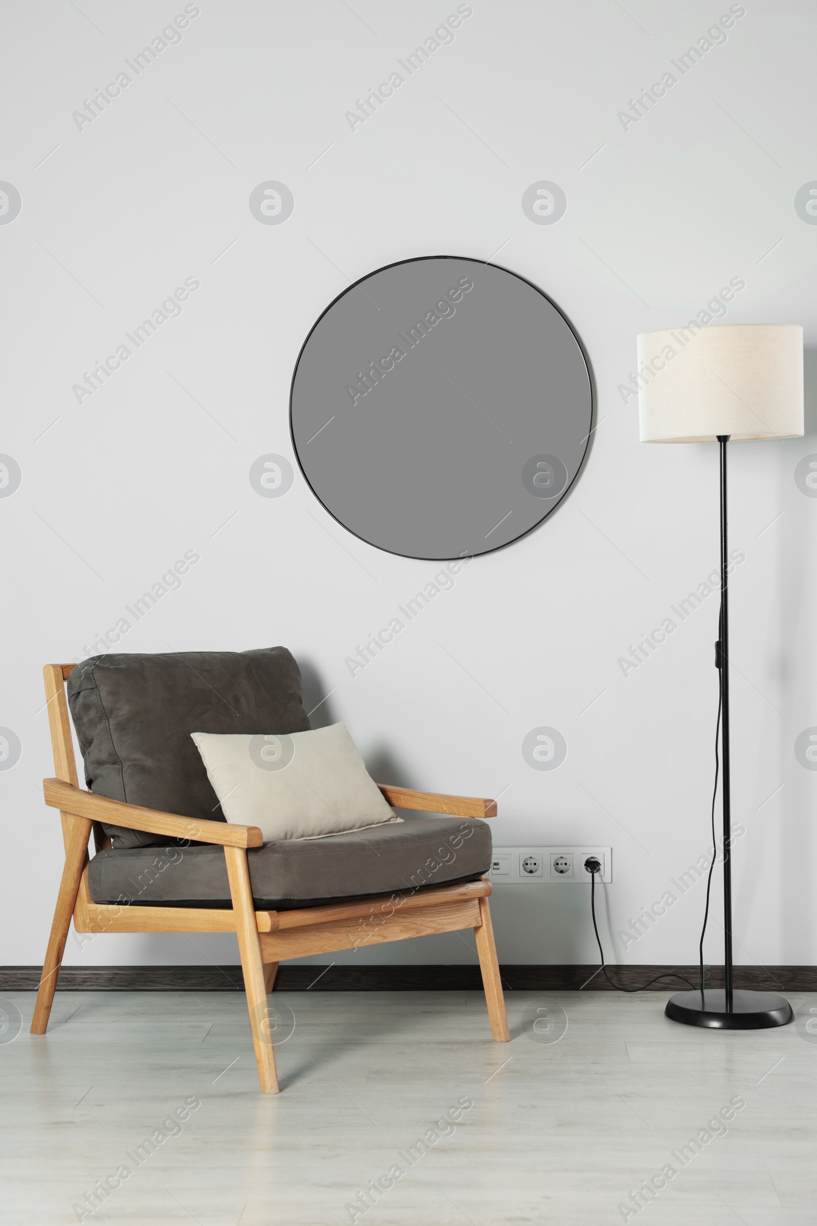 Photo of Stylish round mirror on white wall over armchair in room