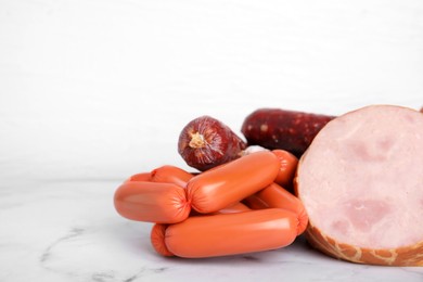Photo of Different types of sausages on white marble table, space for text