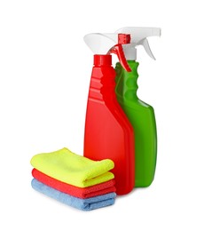 Photo of Spray bottles and stack of car wash cloths on white background