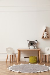 Photo of Cute child room interior with furniture, toys and wigwam shaped shelf on white wall