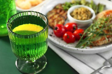 Photo of Delicious drink with tarragon in glass on green table, closeup. Space for text