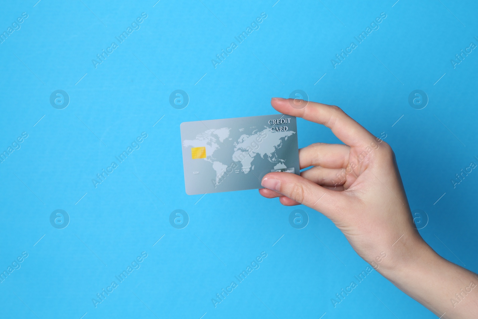 Photo of Woman holding credit card on light blue background, closeup