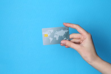 Photo of Woman holding credit card on light blue background, closeup