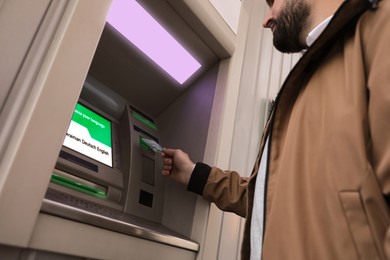 Image of Man inserting credit card into cash machine outdoors, low angle view