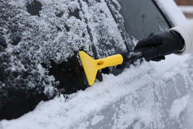 Photo of Man cleaning snow from car outdoors, closeup