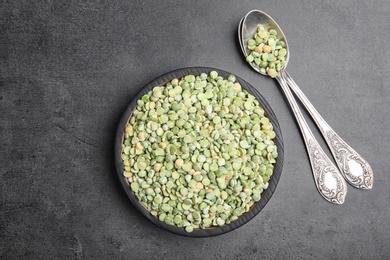 Photo of Plate and spoons with dried peas on grey background, top view