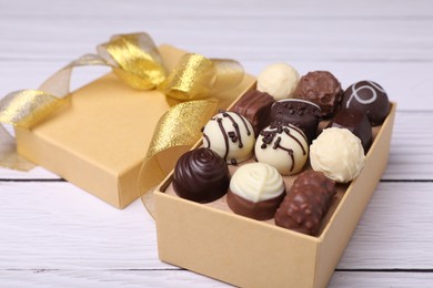 Photo of Box with tasty chocolate candies on white wooden table, closeup